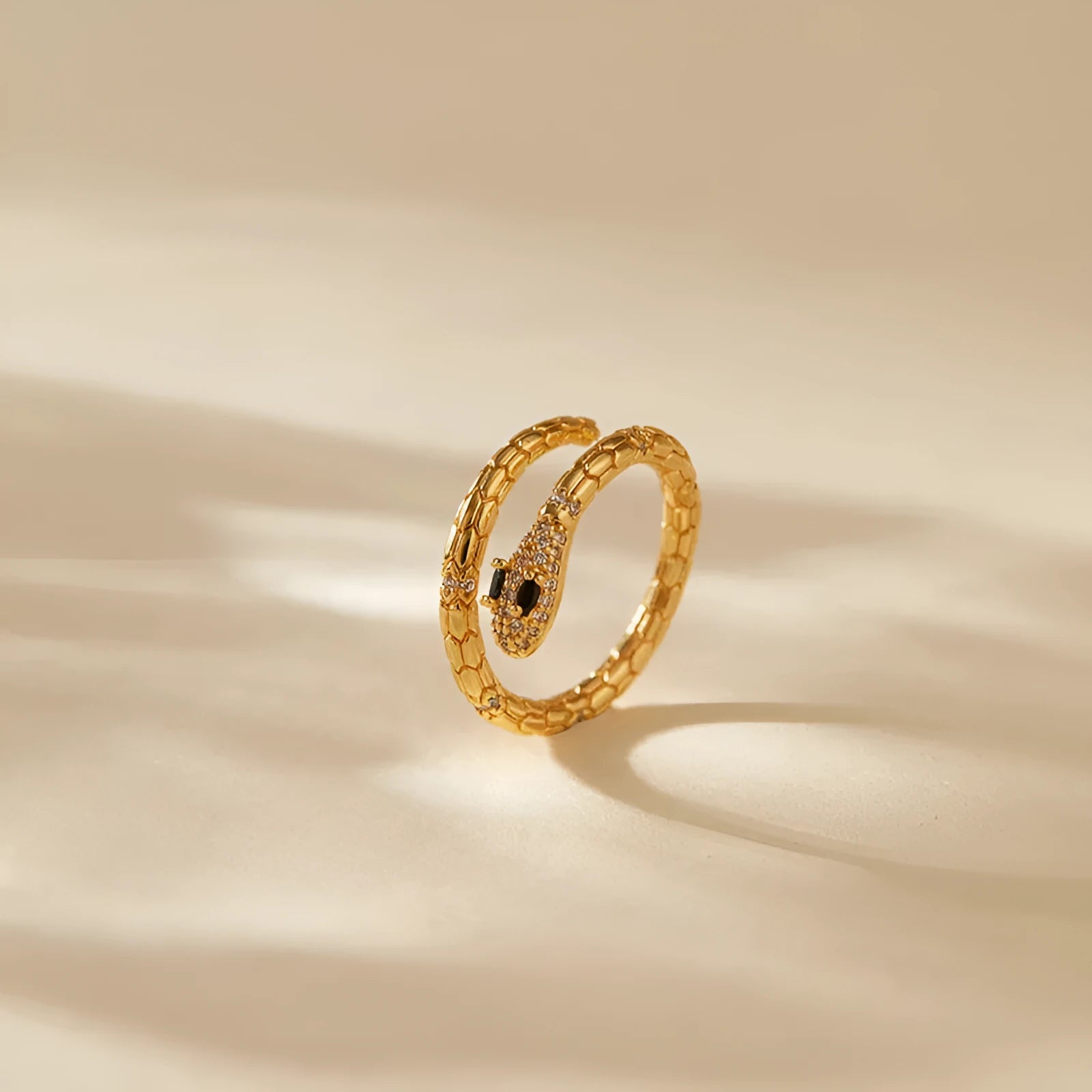 Snake-shaped adjustable copper ring with gold colour finish on a model's index finger.