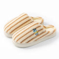 A pair of colourful vertically striped cotton flip flop slippers for adults on a plain background.
