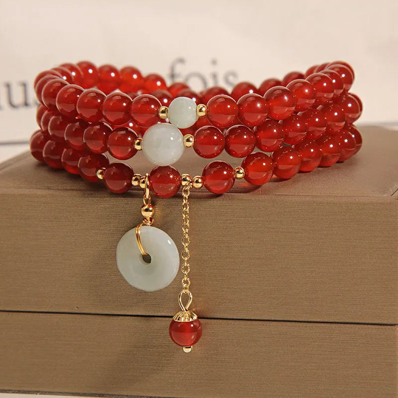 Women's multi-layer red agate crystal bracelet with adjustable closure on a wrist.