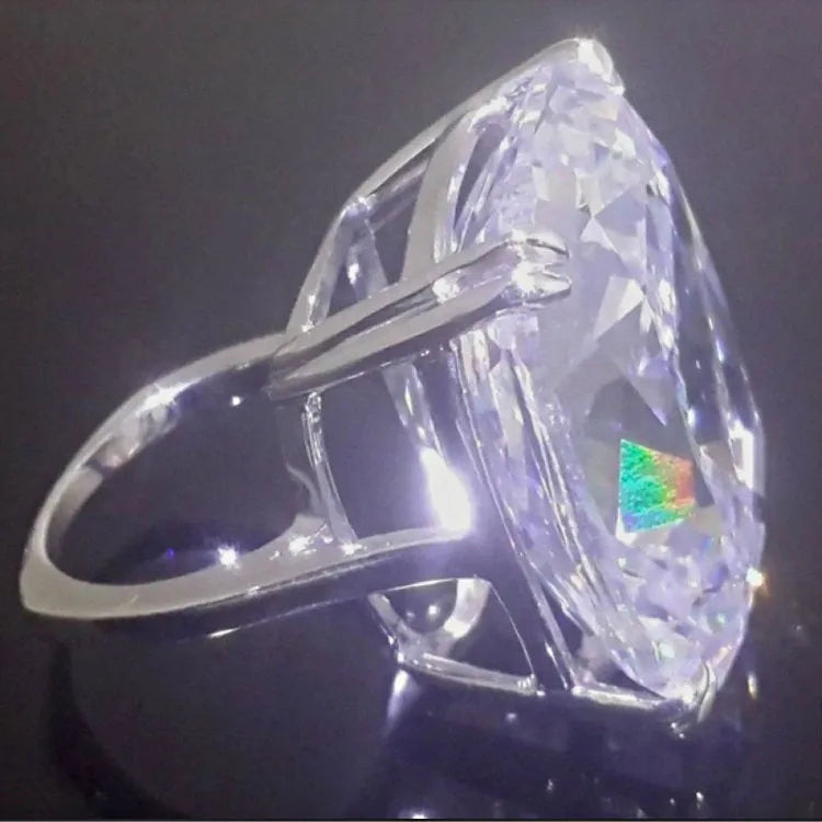Simple white gold colour ring with an inlaid square diamond geometric design, shown on a model's hand.