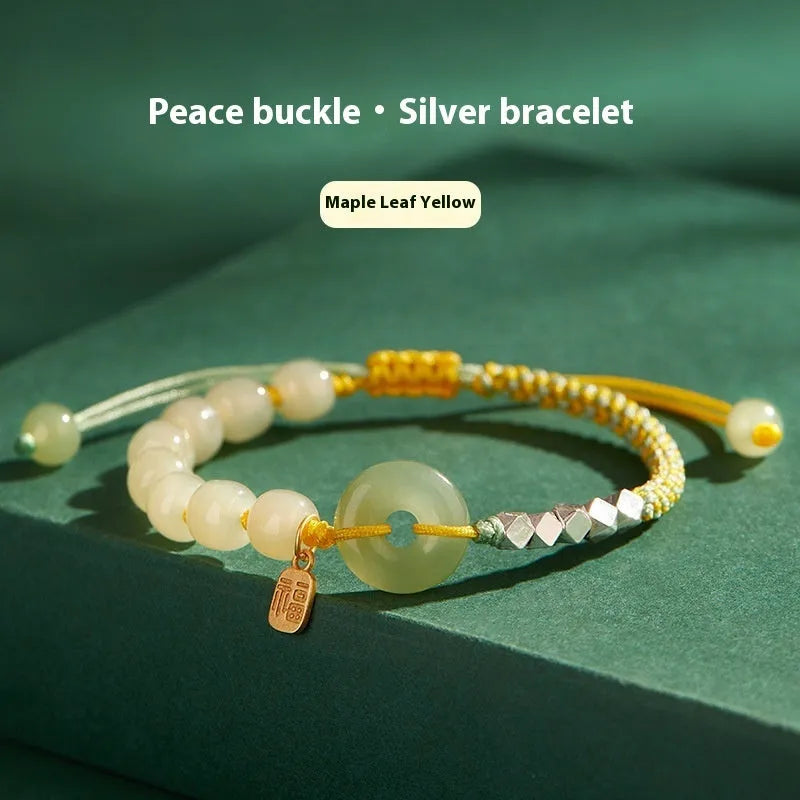 Woven bracelet with a natural Hetian jade flower charm and safety buckle in maple leaf yellow.