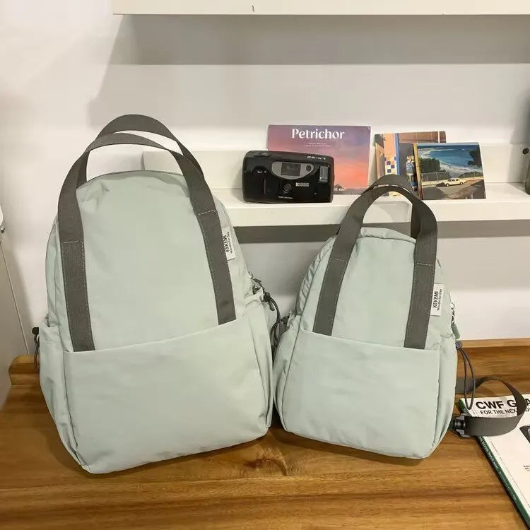 Solid colour nylon backpack in blue with curved straps and a lock, shown in a travel setting.