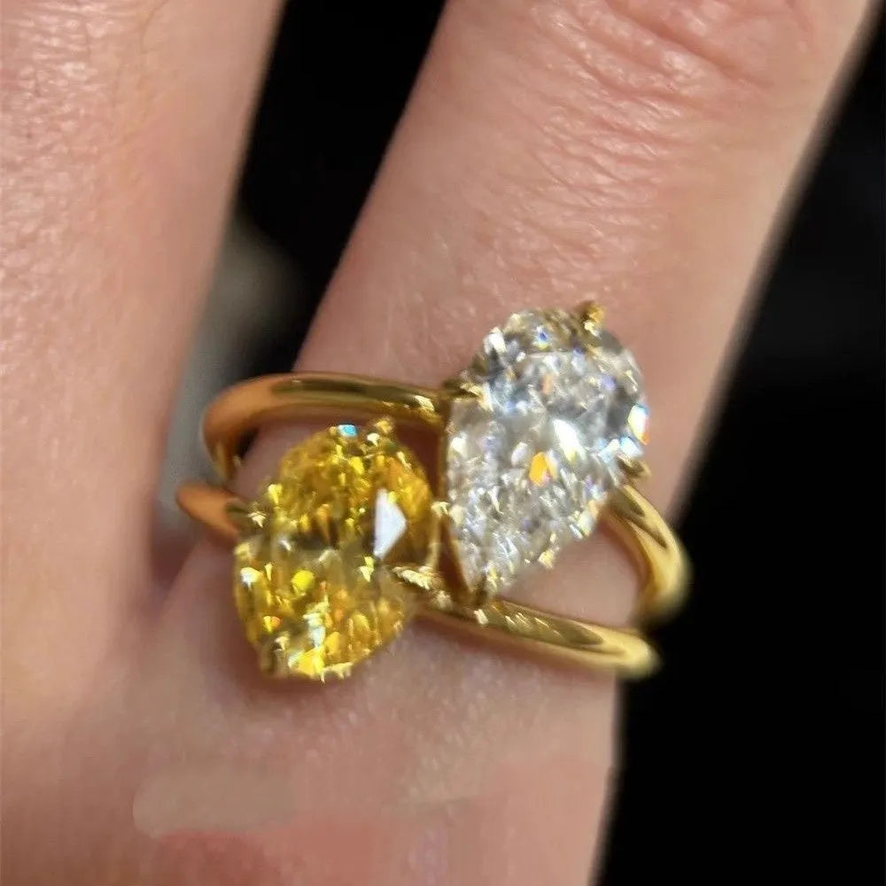 Geometric open copper ring with two sparkling zircon stones in a water drop setting on a model's finger.
