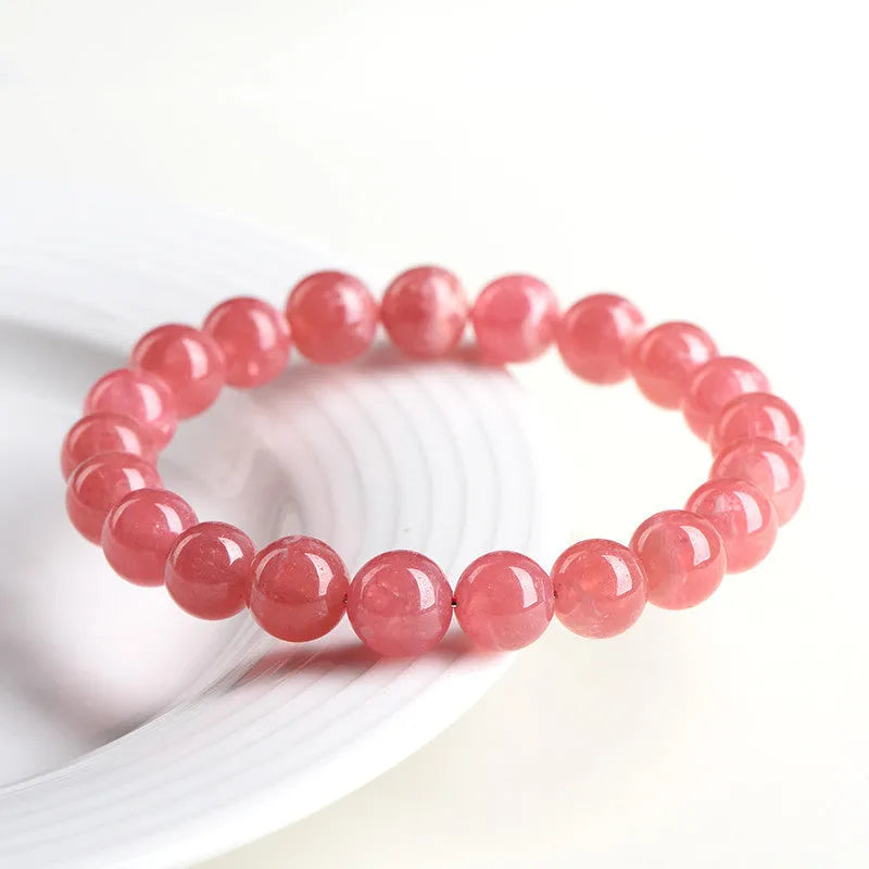 Women's geometric rhodochrosite crystal bracelet with a Longevity Lock centrepiece on a white background.