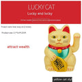 Small yellow solar powered Maneki Neko lucky cat decoration waving its arm.