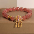 Women's strawberry quartz dream catcher ball pendant bracelet on wrist.