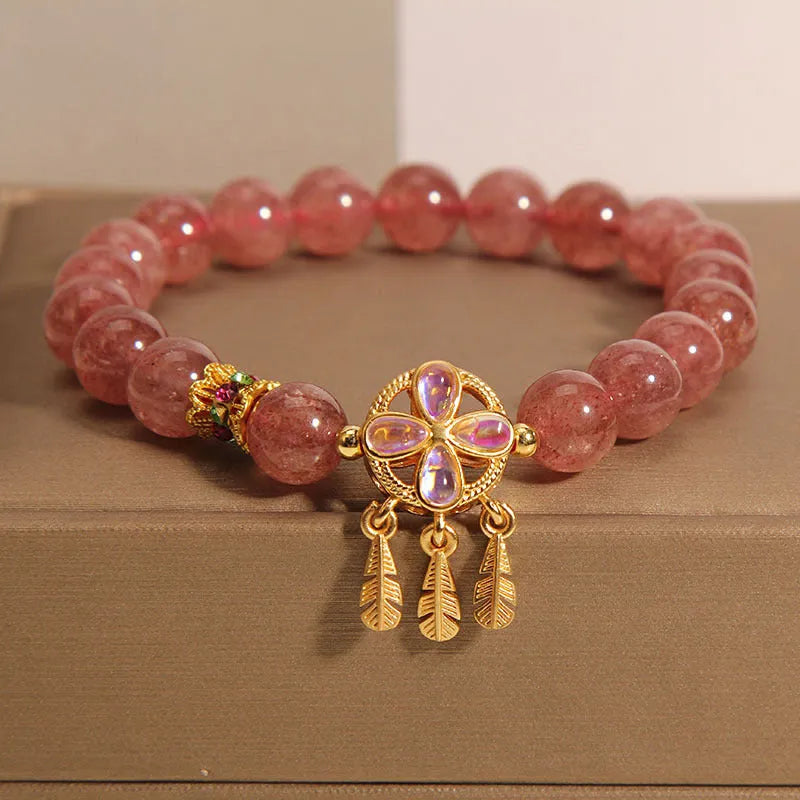 Women's strawberry quartz dream catcher ball pendant bracelet on wrist.