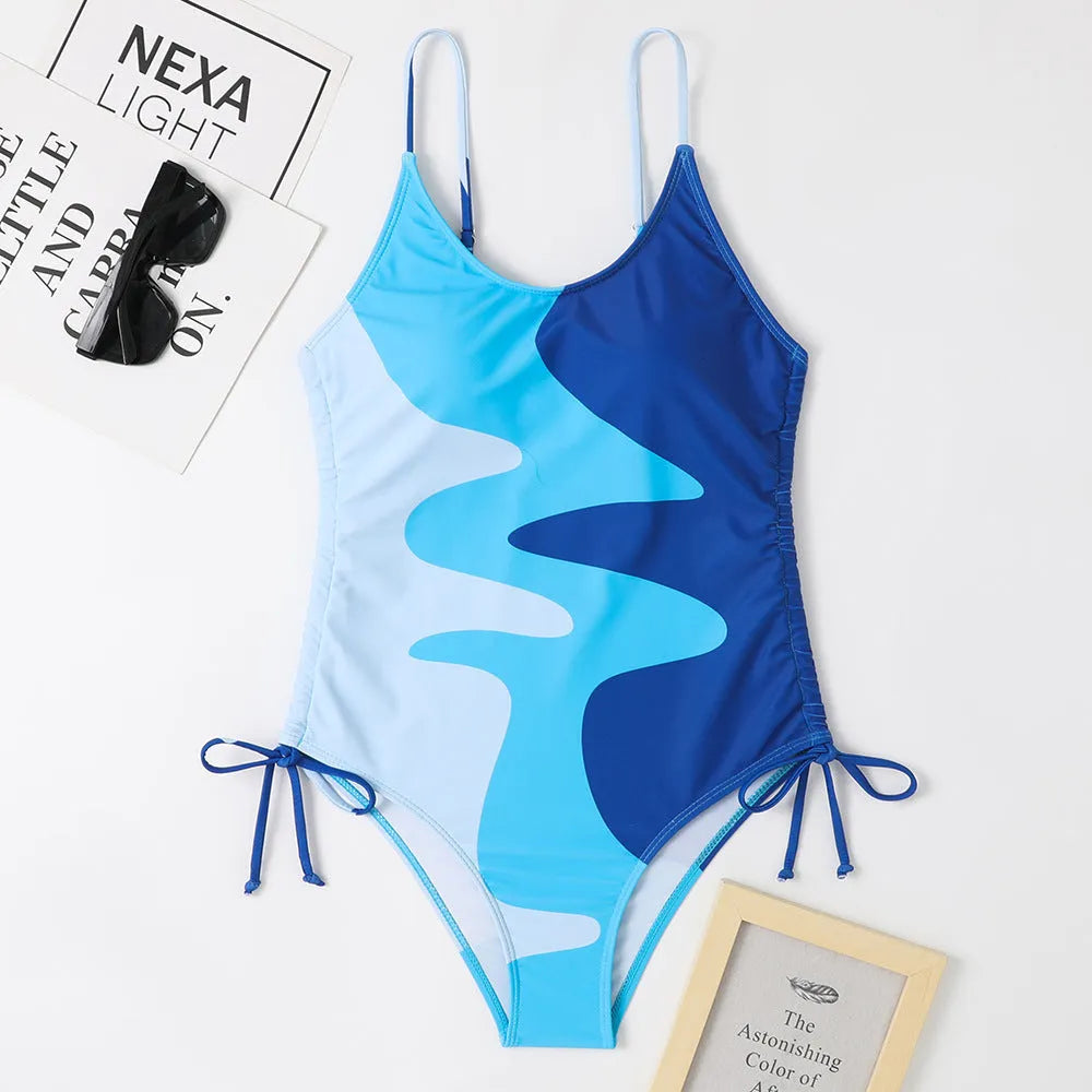 Women's blue sleeveless backless one-piece swimsuit with a striped print on a mannequin.