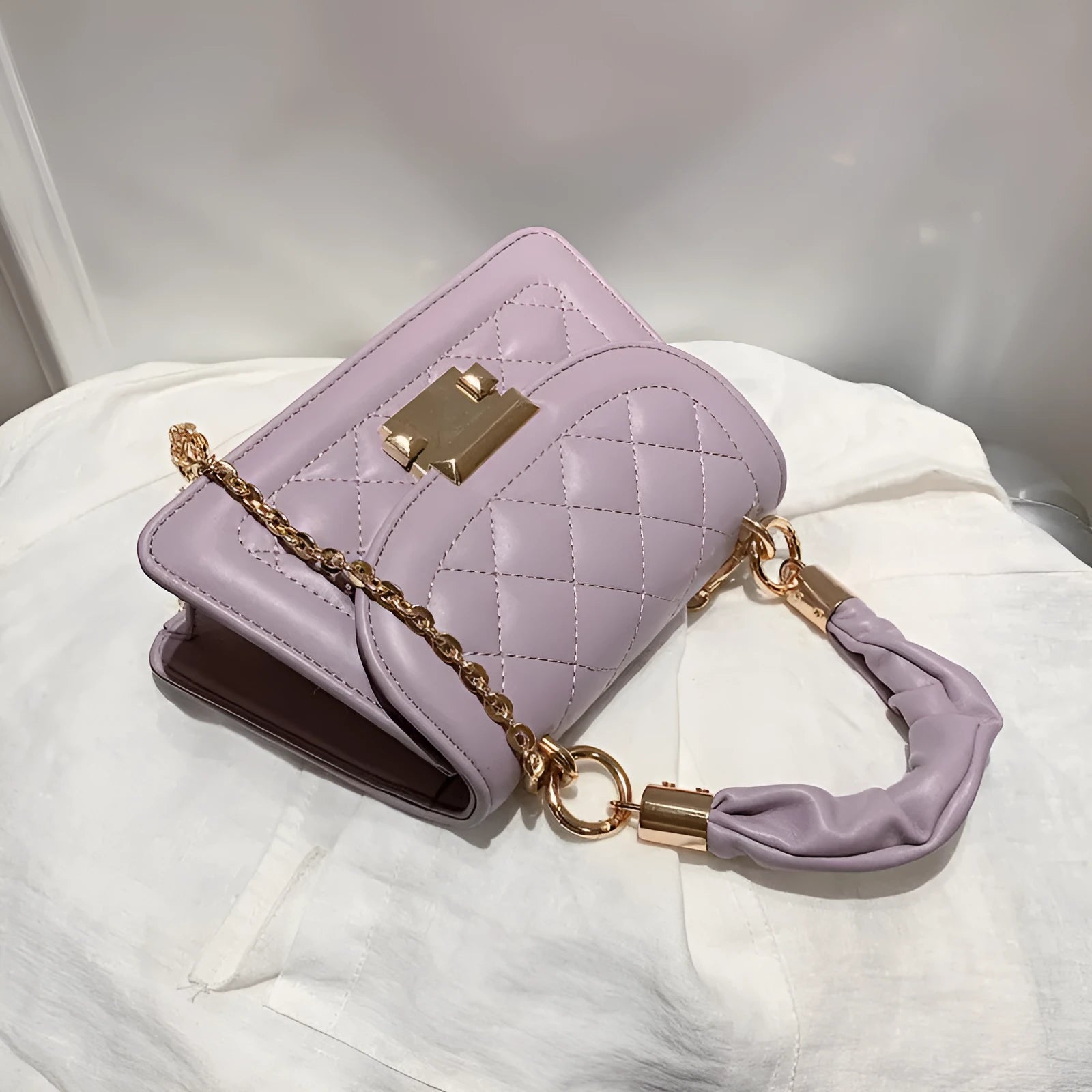 Purple trapezoidal square messenger bag with long crossbody strap shown alongside black and beige colour options