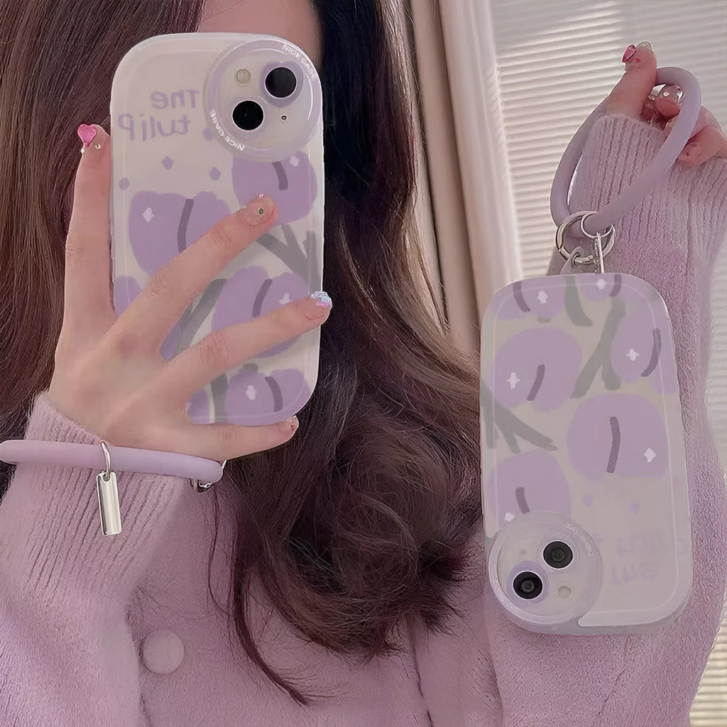 Clear purple tulip printed iPhone case with attached adjustable wrist strap on a table.