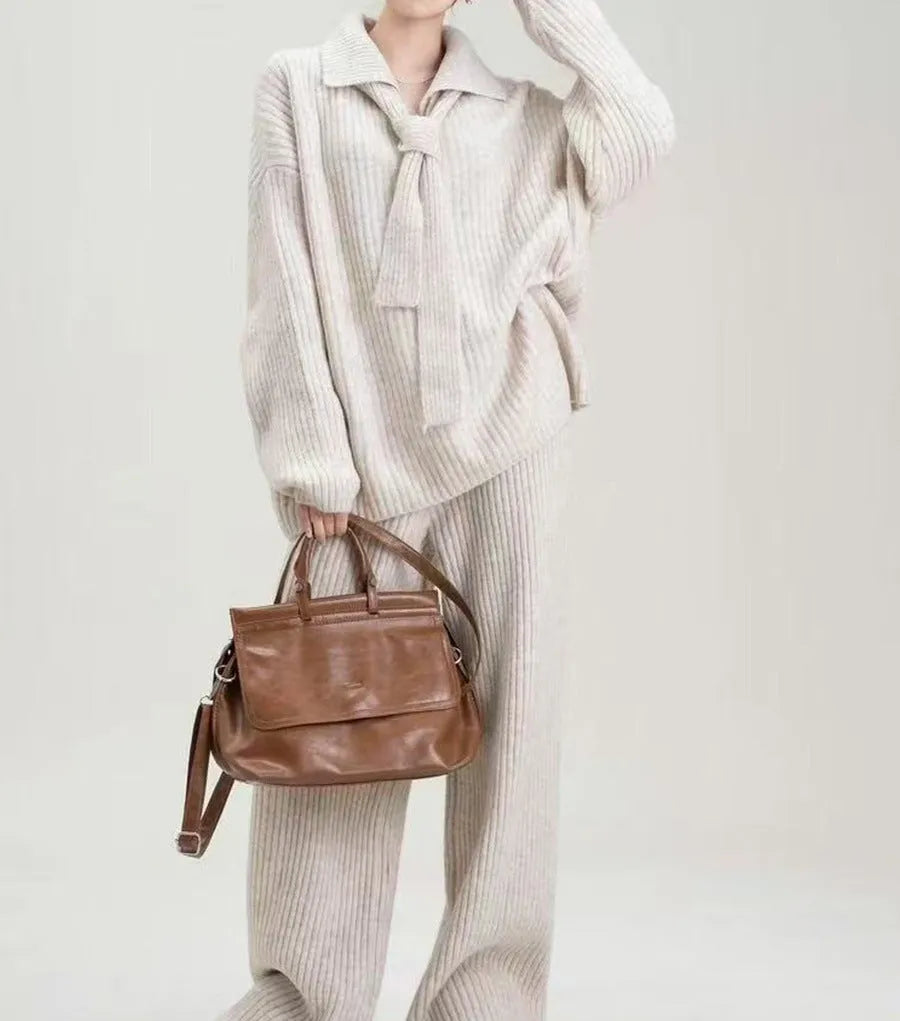 Beige women's knitted acrylic sweater and trouser two-piece set laid flat.