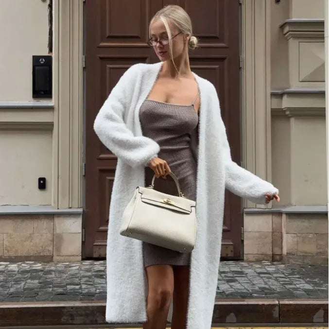 Long white knitted cardigan jacket on a hanger, showing extended length and loose fit.