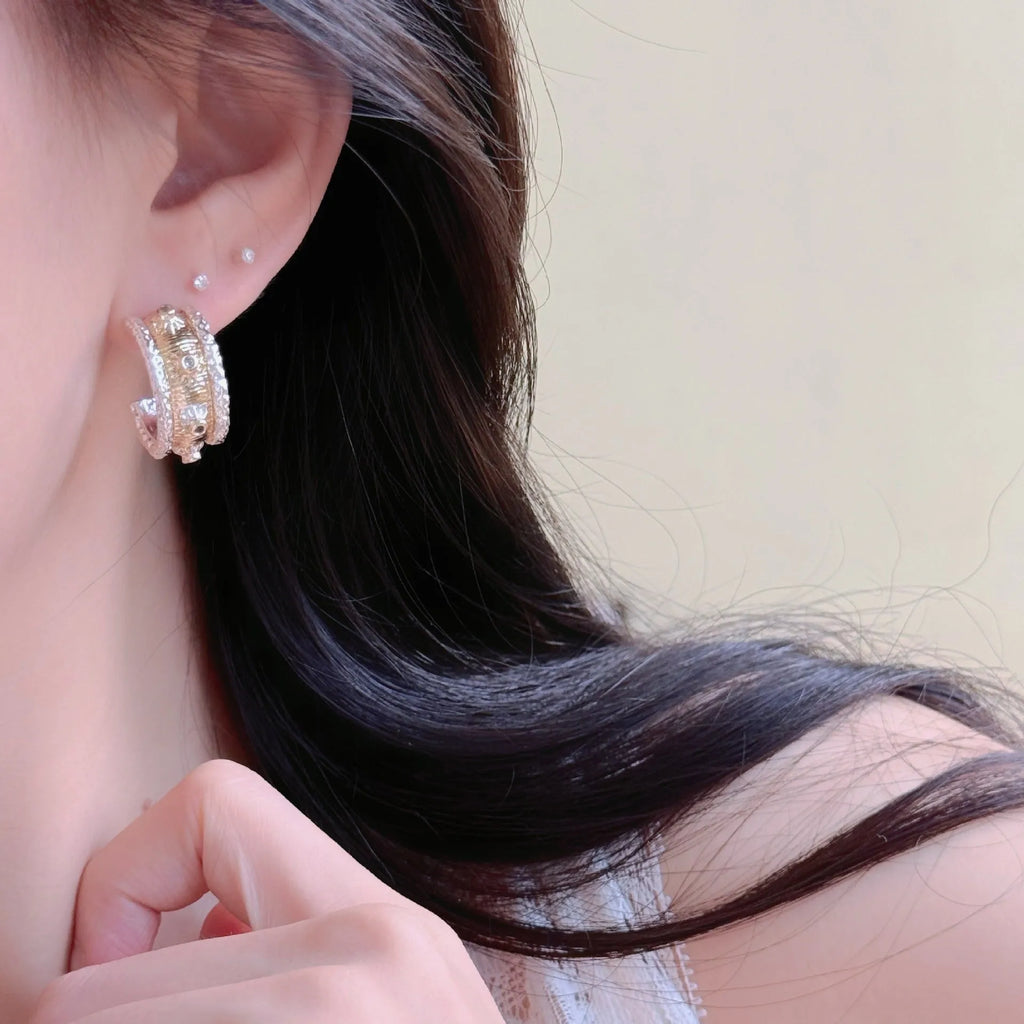 Gold and silver C-shaped brushed ring earrings on display, copper with 925 silver needles