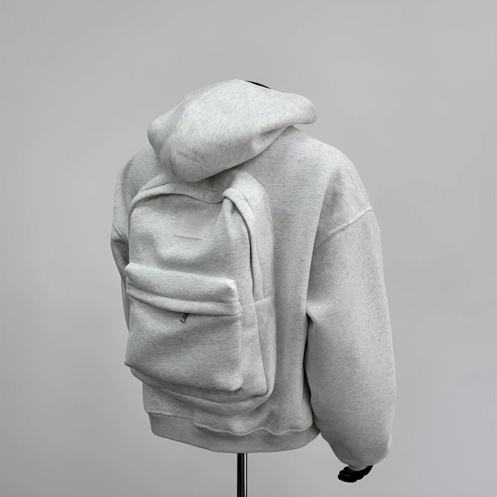 Man wearing a light gray hooded coat with a schoolbag design detail on the back.