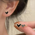 Set of three pairs of heart-shaped alloy earrings in gold, black, black and white, or pink colours