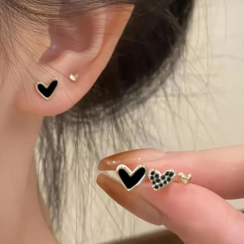 Set of three pairs of heart-shaped alloy earrings in gold, black, black and white, or pink colours