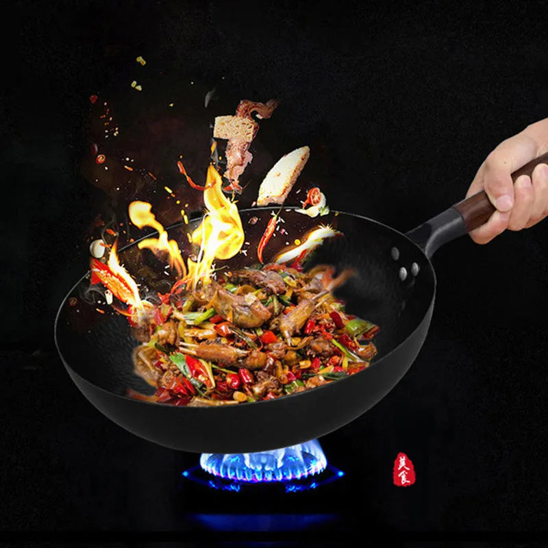 Traditional black iron wok with a long wooden handle on a kitchen counter.