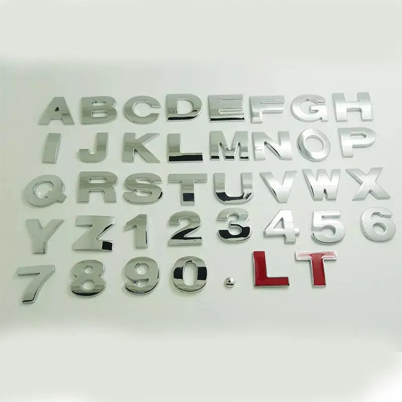 Close-up of a black zinc alloy 3D letter 'A' car bumper sticker on a silver vehicle panel.