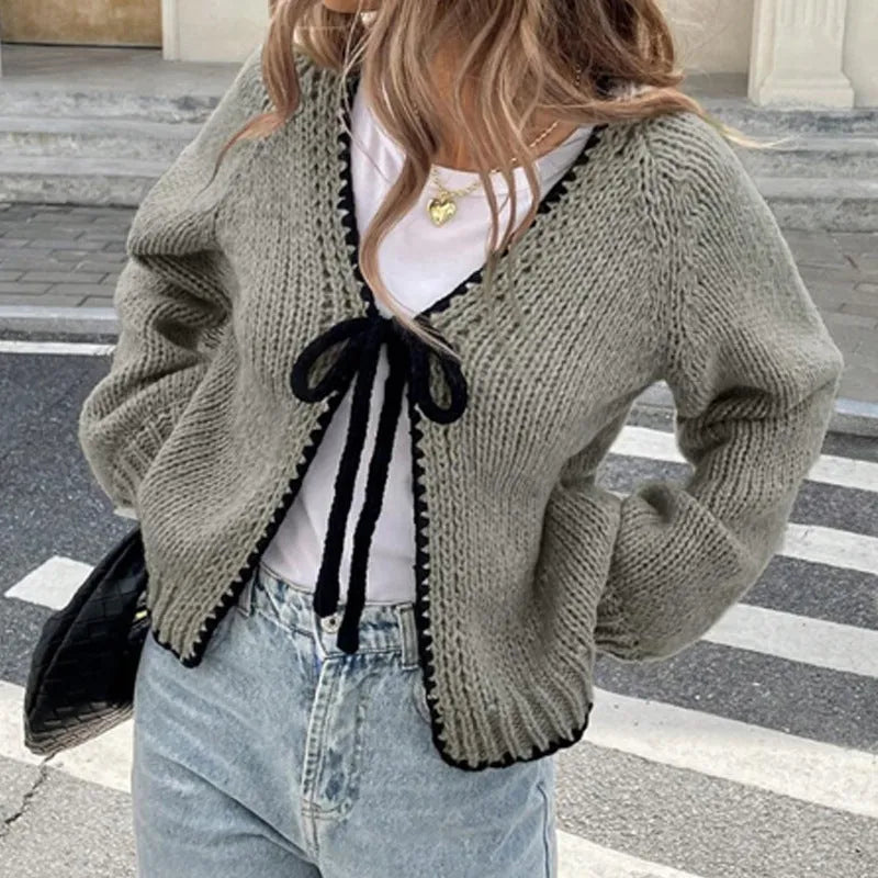 A solid colour loose-fit cardigan with long sleeves and small crochet flower details on the front.
