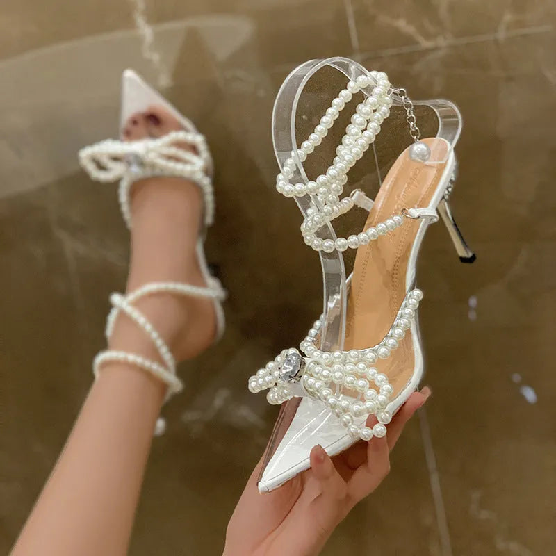 Women's silver ankle-strap buckle sandals with pointed toe and pearl detail on a white background