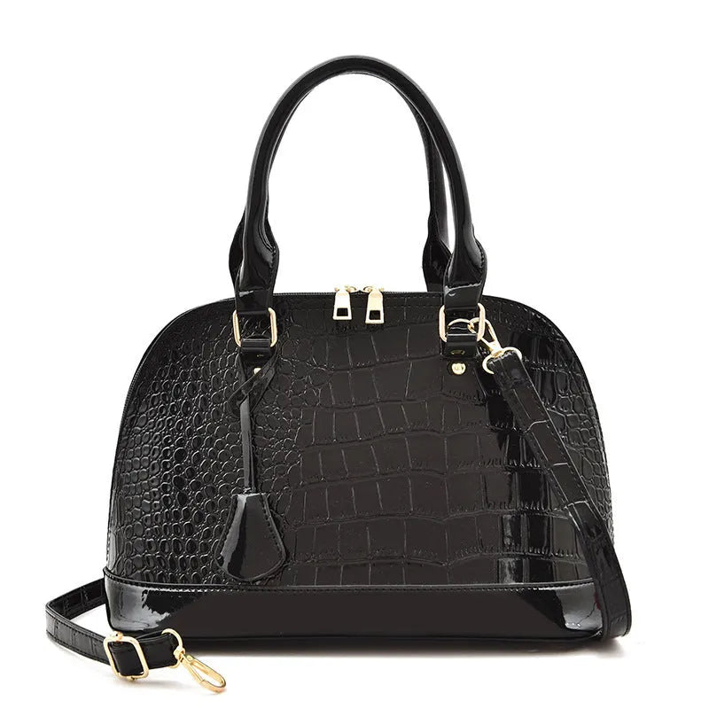 Shiny black structured shell shape crossbody shoulder bag showing large capacity and interior lining.