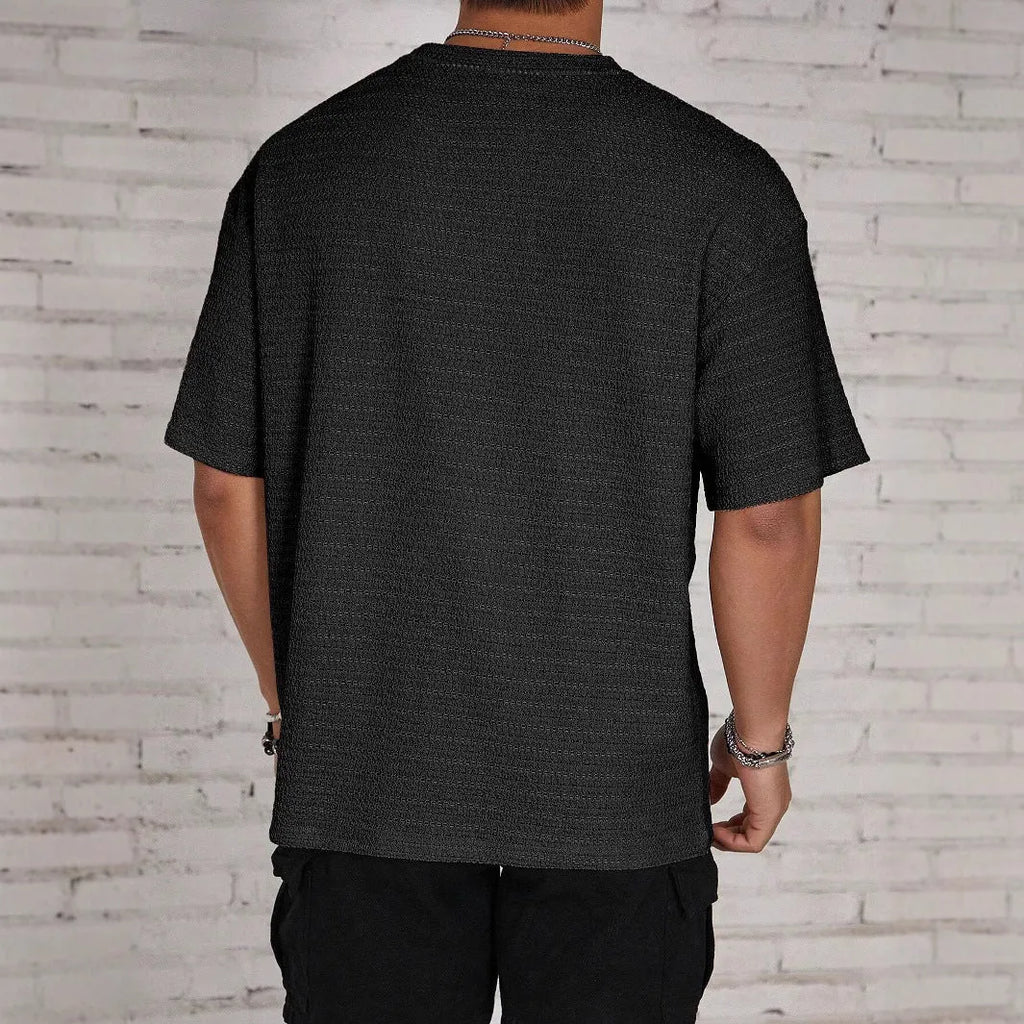 Man wearing a loose-fit light blue hollow solid colour men's t-shirt with short sleeves.
