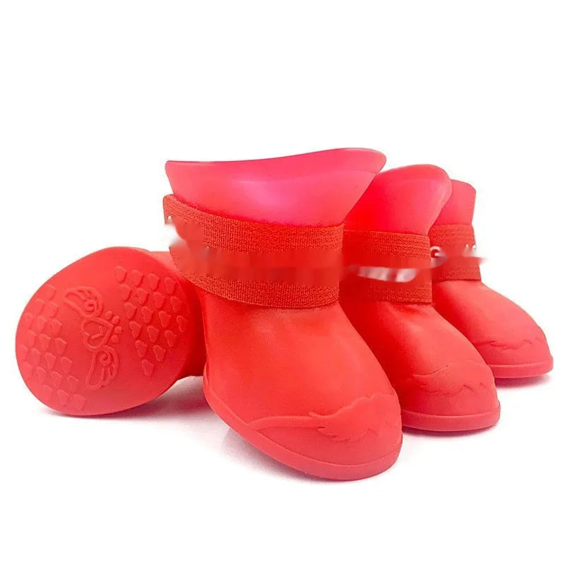 Set of four soft-soled rubber rain shoes for dogs in various colours on a wet surface.