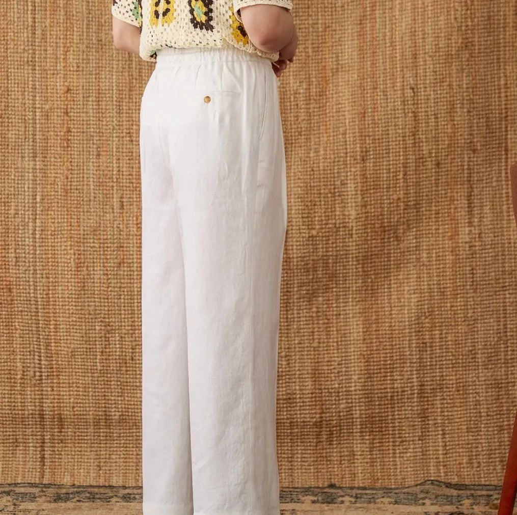 Navy blue linen straight-leg trousers with a high elasticated waistband laid flat.