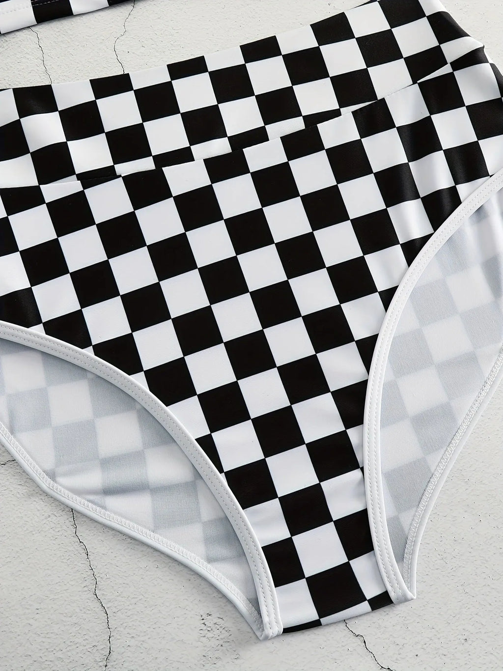 Women's backless one-piece swimsuit with black and white chessboard pattern and sporty suspender straps.