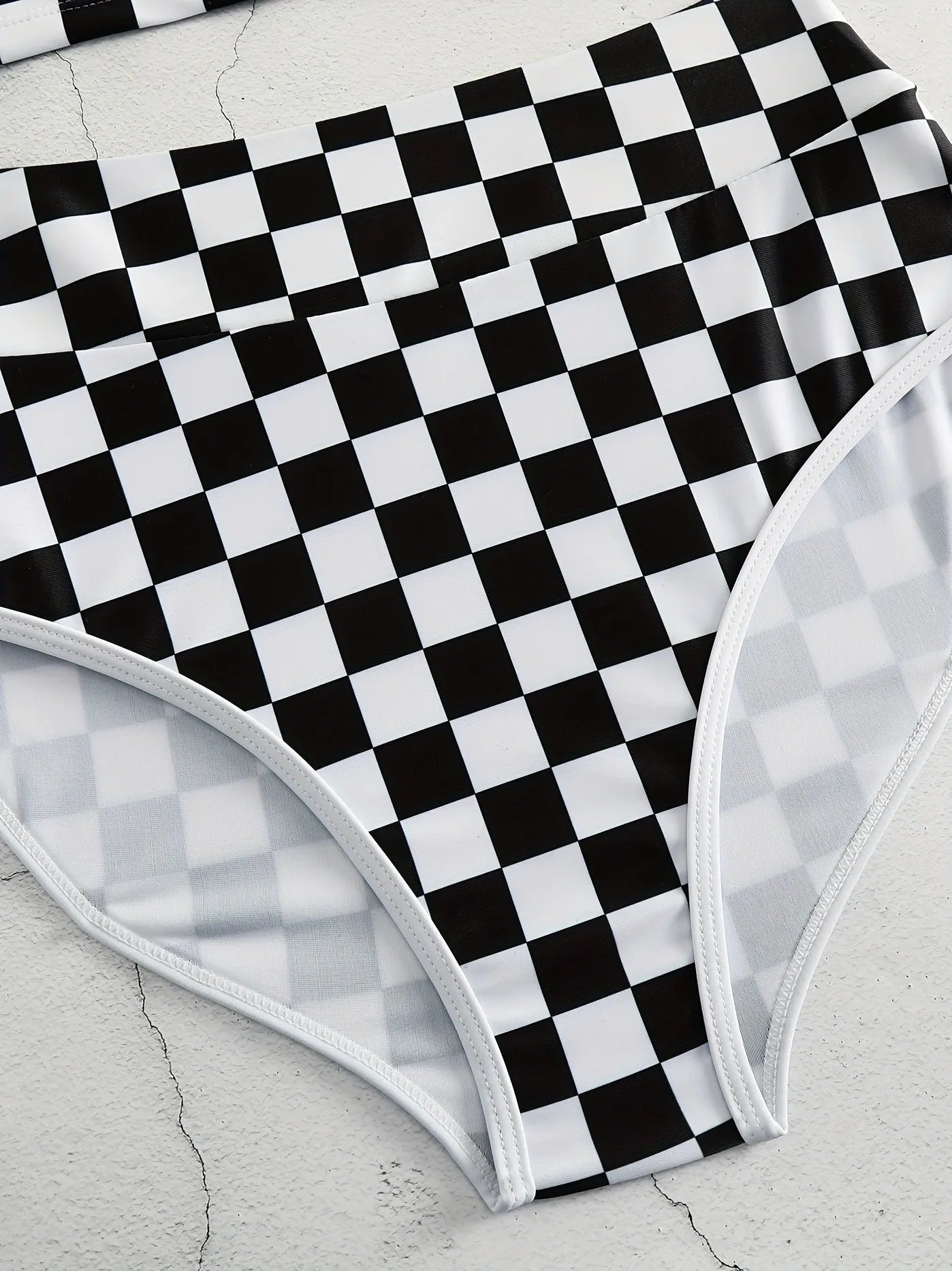 Women's backless one-piece swimsuit with black and white chessboard pattern and sporty suspender straps.