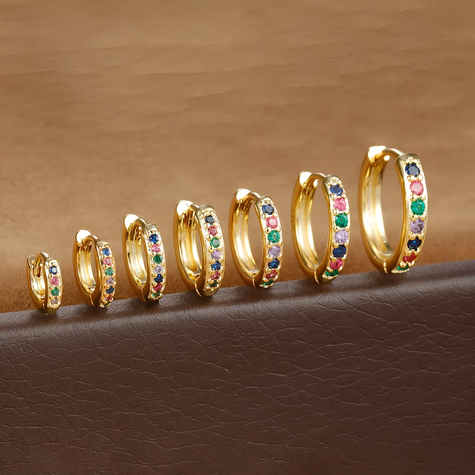 Circle-shaped perforated stud earrings in gold, rose gold, and silver colours on a white background.