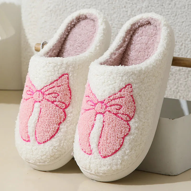 A pair of pink cartoon bow knot suede slippers with a TPR sole, shown from the side.
