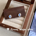 Sterling silver earrings with oval blue diamond in heart wire wrap setting