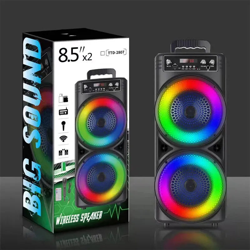 Black portable Bluetooth speaker with double 8-inch speakers, wired microphone, and remote control on a table