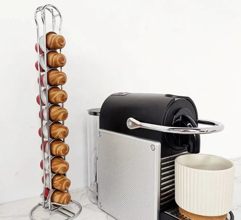 Black wrought iron coffee capsule storage rack holding pods on shelves.