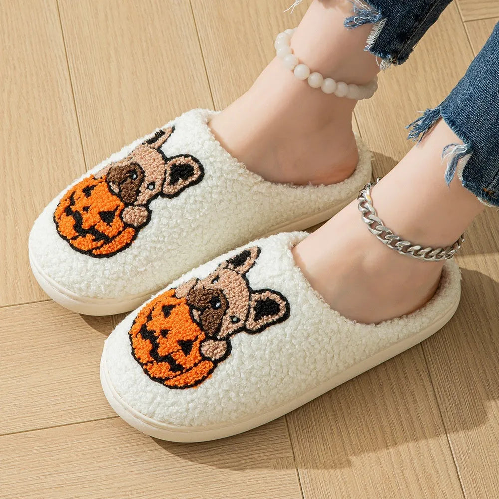 Black plush Halloween slippers with pumpkin print and a thick, textured TPR rubber sole.