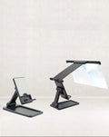 Black folding mobile phone screen magnifier and adjustable holder on a desktop.