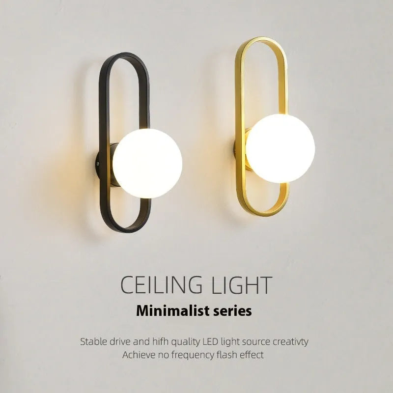 Modern minimalist wall lamp with clear glass shade and black iron mount, showing three light colour settings.