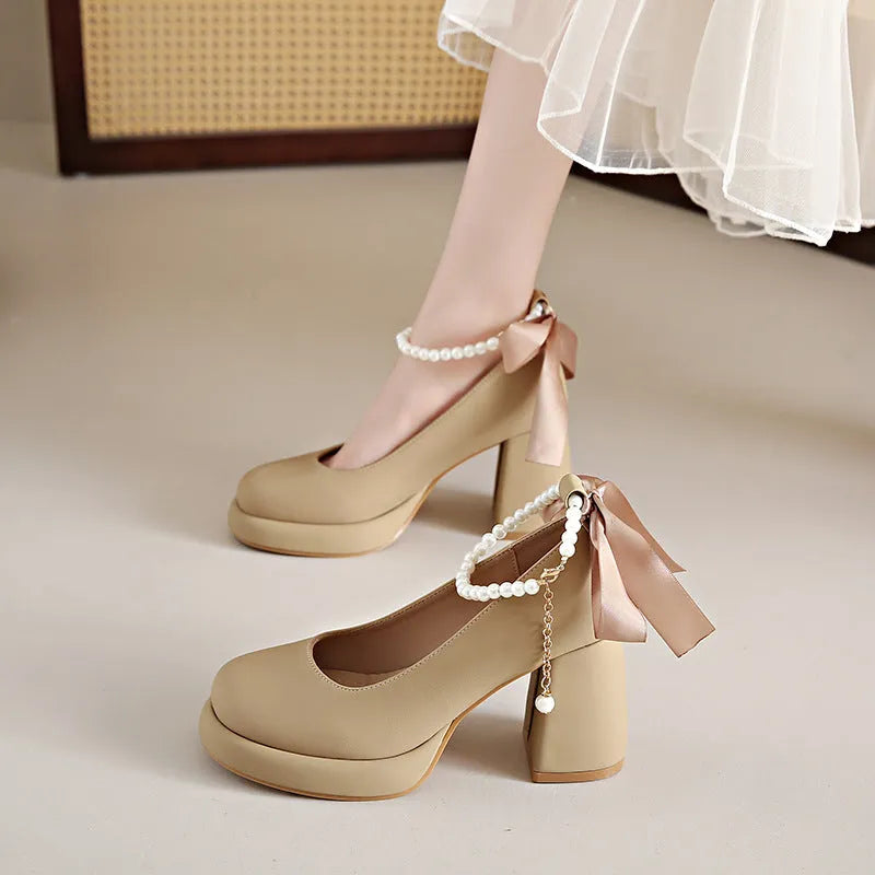 Women's beige Mary Jane shoes with chunky heel and silver ankle strap buckle on a wooden floor.