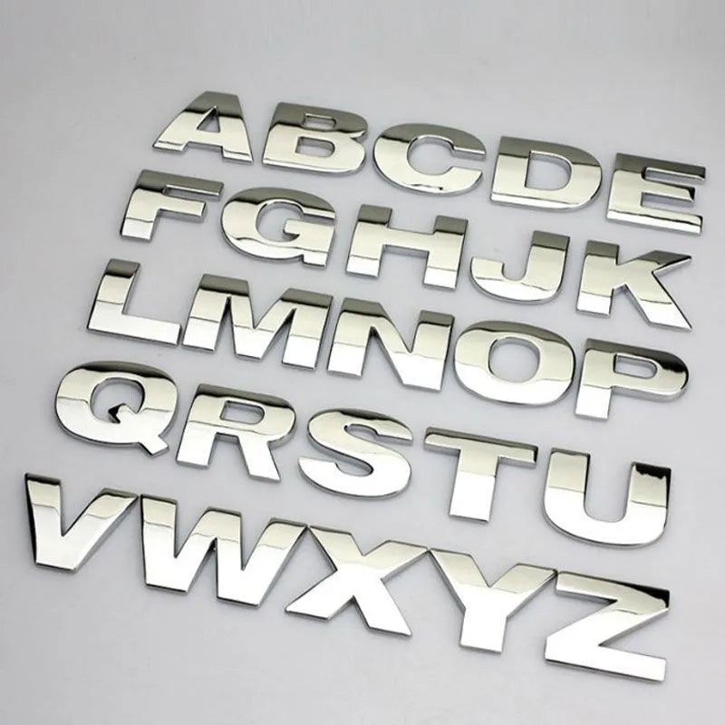 Close-up of a black zinc alloy 3D letter 'A' car bumper sticker on a silver vehicle panel.