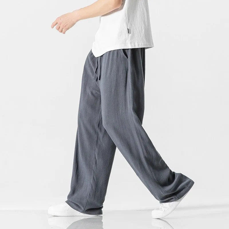 Man wearing beige loose-fit cropped straight-leg trousers made from bamboo fibre with a drawstring waist.