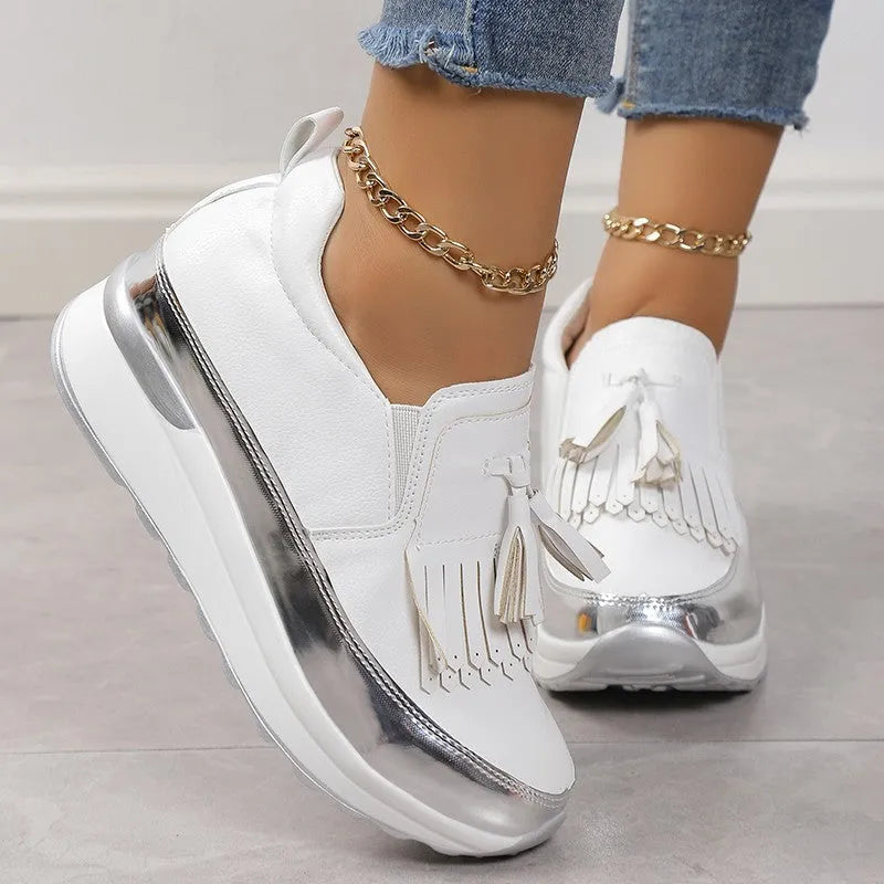 Women's black casual platform shoes with tassel detail and muffin wedge heel on a white background
