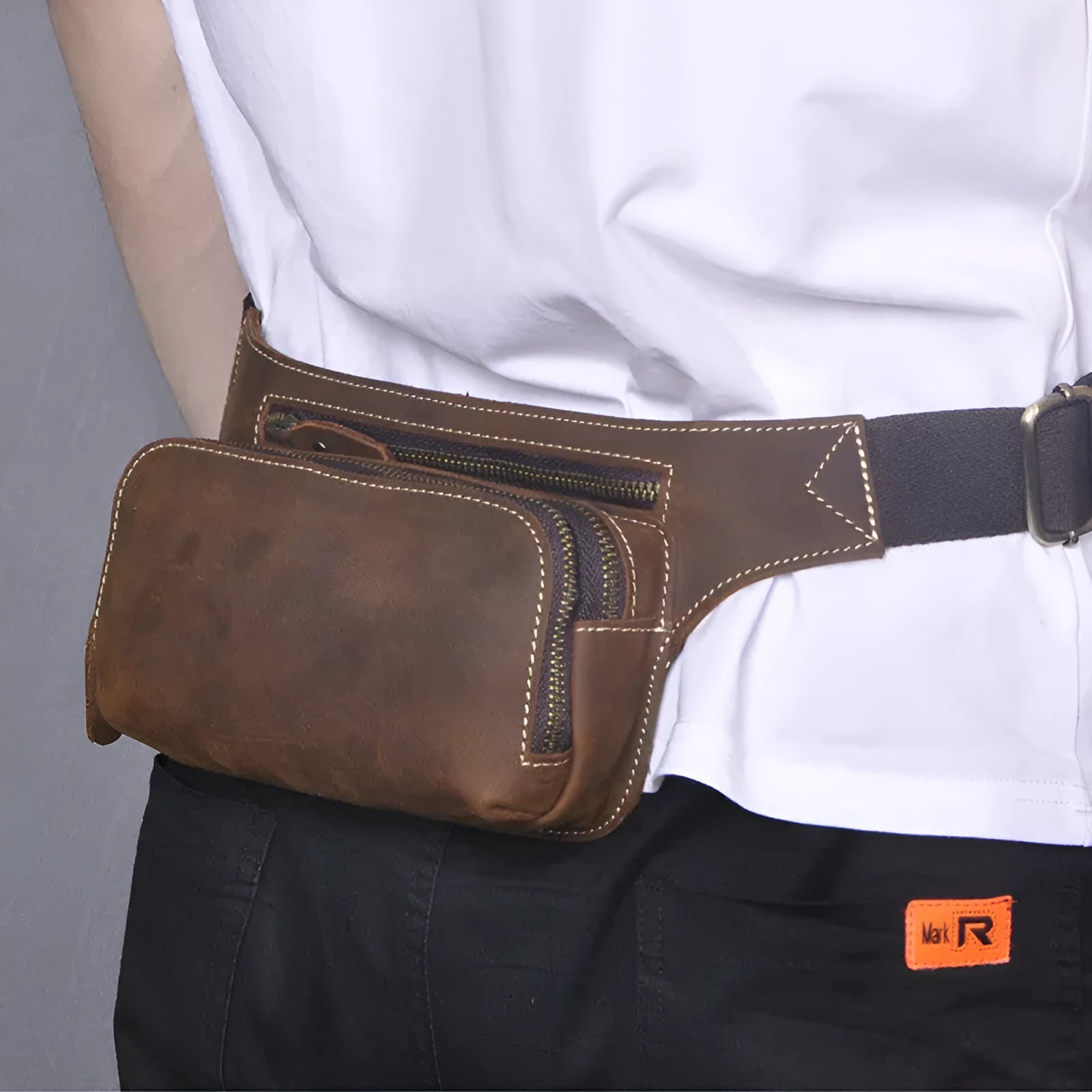 Brown cowhide leather men's waist bag showing pull-closure, worn on hip, with internal phone pouch visible.