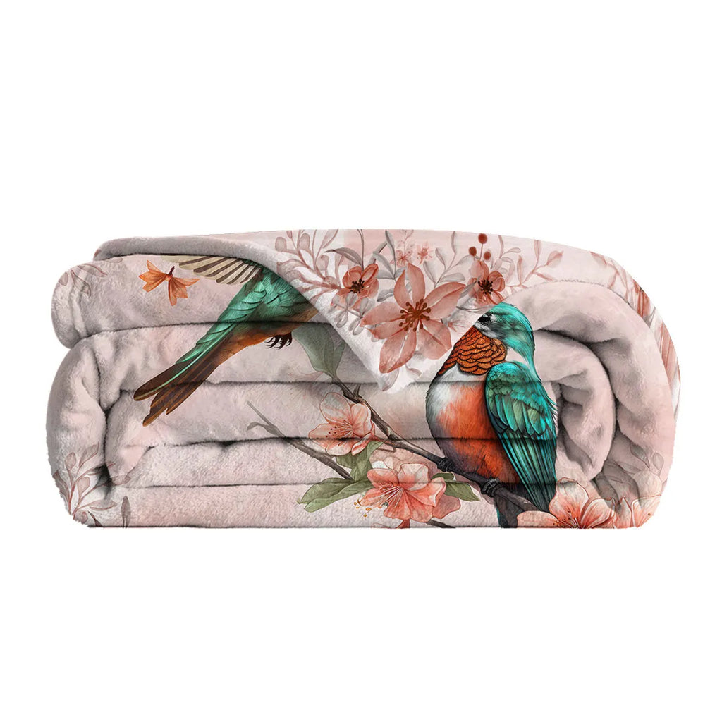 Pink hummingbird floral fleece throw blanket on sofa with floral print