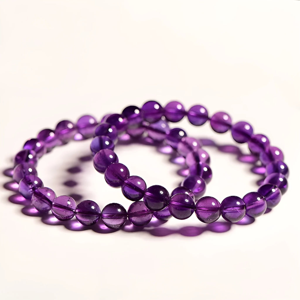 Close-up of a polished natural amethyst bead stretch bracelet on a wrist, showing deep violet colour and elasticated band.