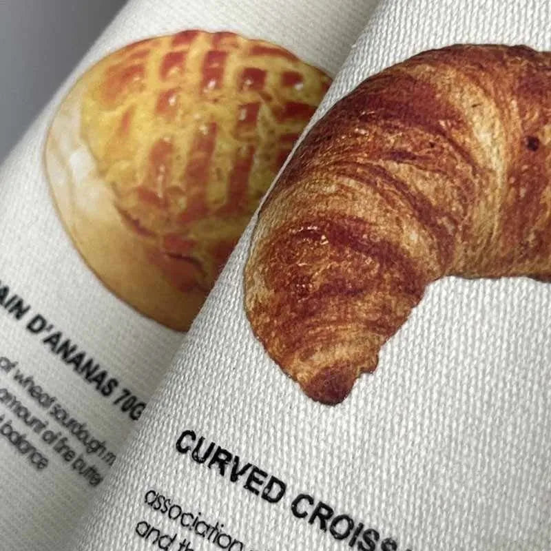 Beige canvas shoulder tote bag with a decorative bread and croissant print design.