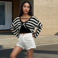 A woman wearing a cropped black and white striped long-sleeved sweater with a front and back exposed-navel design.