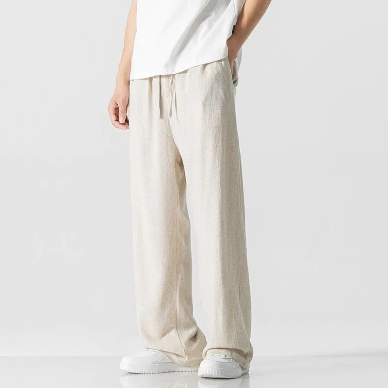 Man wearing beige loose-fit cropped straight-leg trousers made from bamboo fibre with a drawstring waist.