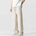 Man wearing beige loose-fit cropped straight-leg trousers made from bamboo fibre with a drawstring waist.