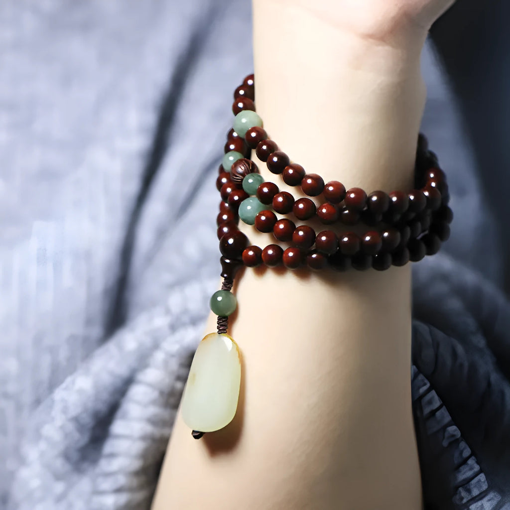 Close-up of a hand-carved rosewood beaded bracelet with 108 6mm beads and a carved Hotian jade pendant.